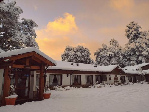 a building covered in snow with trees in the background at Hosteria El Condado in San Carlos de Bariloche