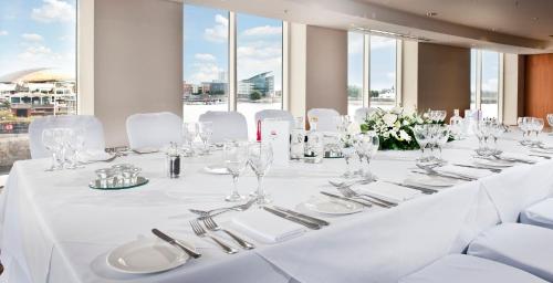 a long white table with white chairs and glasses at voco St. David's Cardiff by IHG in Cardiff
