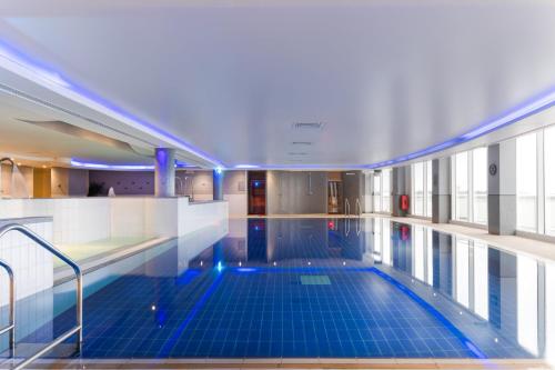 a swimming pool with blue tiles in a building at voco St. David's Cardiff by IHG in Cardiff