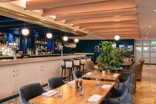 a restaurant with wooden tables and chairs and a bar at voco St. David's Cardiff by IHG in Cardiff