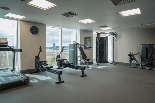 a gym with treadmills and ellipticals in a room with windows at voco St. David's Cardiff by IHG in Cardiff