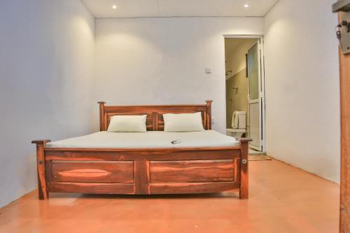 a bedroom with a wooden bed with white sheets at Wild Earth Ceylon Leisure - Yala in Katagamuwa