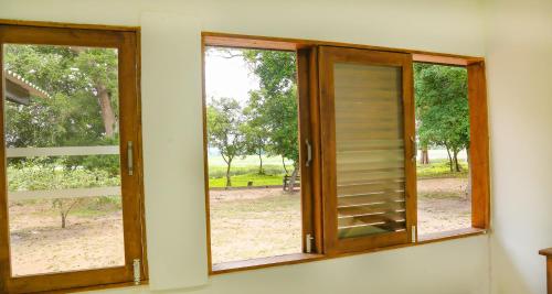 two windows with wooden doors in a room at Wild Earth Ceylon Leisure - Yala in Katagamuwa