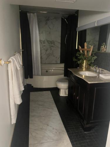 a bathroom with a toilet and a tub and a sink at Blarney Place Retreat in Vernon