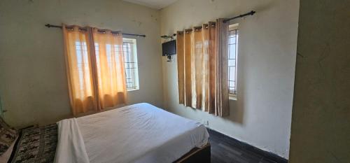 a bedroom with a bed and two windows at Stay awhile in Ooty