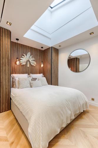 une chambre avec un grand lit blanc et un miroir dans l'établissement Charming Pied à Terre near Montmartre, à Paris