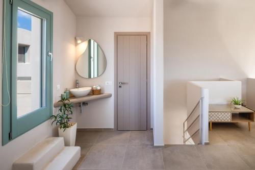 a bathroom with a door and a sink and a mirror at Dune Santorini Villa in Vlychada