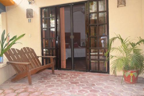 a porch with a wooden bench and a door at Hotel Casa el Moro in Puerto Morelos