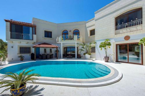 a large house with a swimming pool in front of it at Villa Alexandra: Sea Views Pool Jacuzzi Sauna in Mellieħa