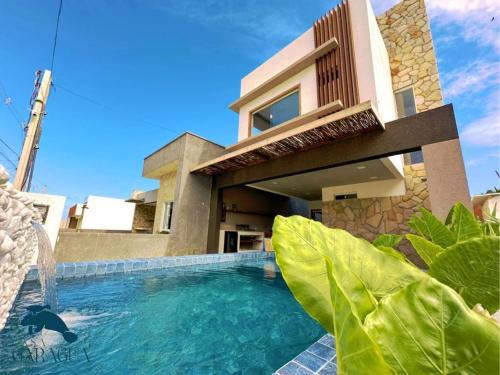 a house with a swimming pool in front of a house at Casa a 1200m da Praia do Patacho - Casa Garaguá in Pôrto de Pedras