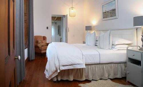 a bedroom with a large white bed and a chair at Dennehof Karoo Guesthouse in Prince Albert