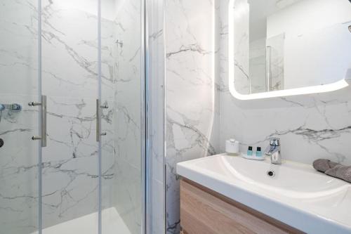 une salle de bain blanche avec un lavabo et une douche dans l'établissement Charmant 2P au cœur de Nice, à Nice