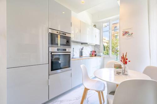 une cuisine blanche avec une table et des chaises blanches dans l'établissement Charmant 2P au cœur de Nice, à Nice