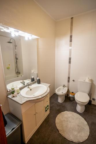 a bathroom with a sink and a toilet and a mirror at Sentidos do Mar - Apartamento em São Miguel in Calhetas