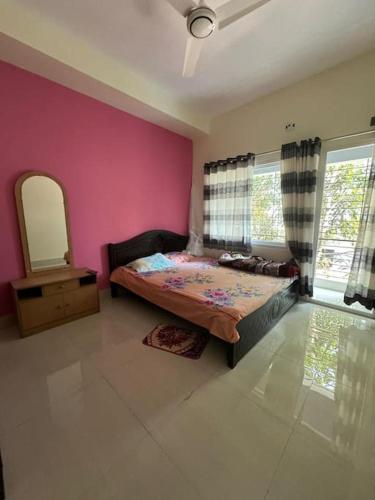 a bedroom with a bed and a pink wall at luxurious apartmnt in city centre in Sylhet