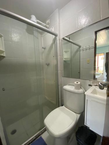 a bathroom with a toilet and a glass shower at Condomínio Merepe Residence in Porto De Galinhas