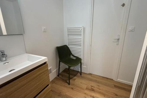 a bathroom with a sink and a green chair at Grande Maison 17 personnes in Arras