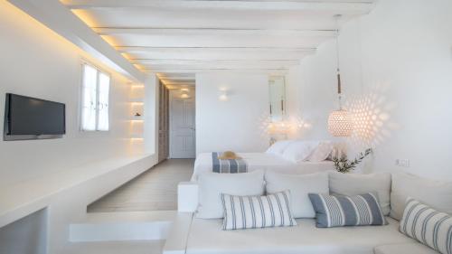 a white living room with a couch and a tv at Villa Marandi Luxury Suites in Stelida