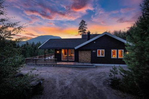 a small house with a sunset in the background at Verhøf Hytte - 9p - With Sauna & Hot Tub in Vradal