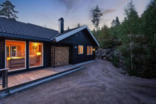 a small black house with a deck in front of it at Verhøf Hytte - 9p - With Sauna & Hot Tub in Vradal