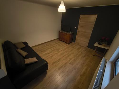 a living room with a black couch and a wooden floor at Maison entière privée in Charleroi
