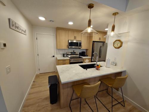 a kitchen with a counter and chairs in a room at A stylish 2 BDR with a blend of cozy and peace! in Calgary