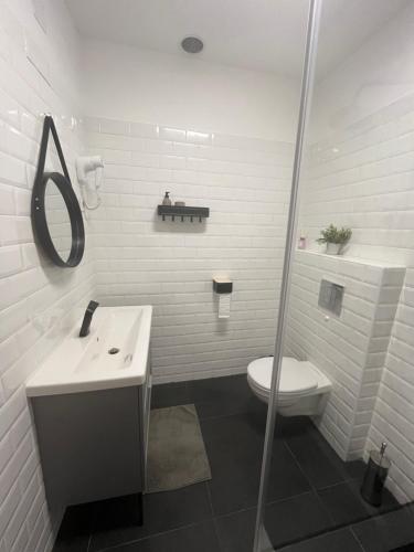 a white bathroom with a toilet and a sink at Kikelet Udvarház in Zánka