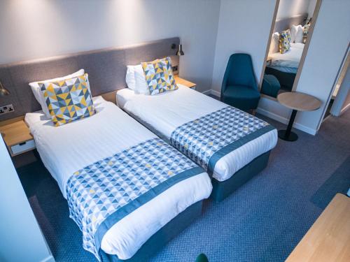 a hotel room with two beds and a chair at Holiday Inn South Normanton M1, Jct.28 by IHG in South Normanton