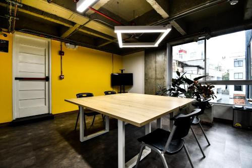 einen Tisch in einem Büro mit Stühlen und einer gelben Wand in der Unterkunft Ulivin Coliving in Manizales