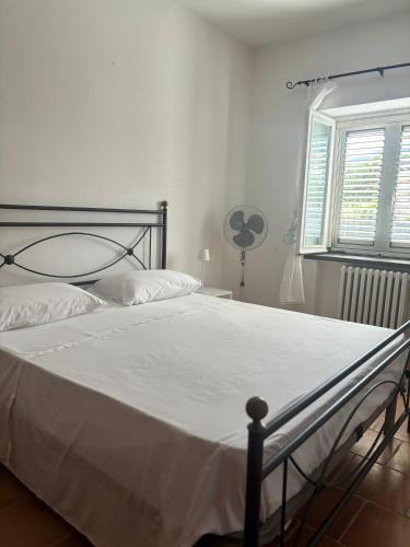 a bedroom with a bed with a white bedspread and a window at Casa Vacanze Primavera in Maratea