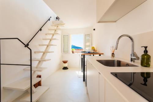 une cuisine avec des placards blancs et un escalier en colimaçon dans l'établissement LA CASETTA DI AZZURRA AP4427 By Riviera Holiday Homes, à Villefranche-sur-Mer
