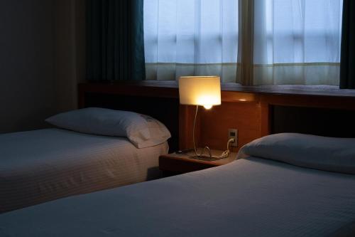 a bedroom with two beds and a lamp and a window at Hotel Abastos Plaza in Mexico City