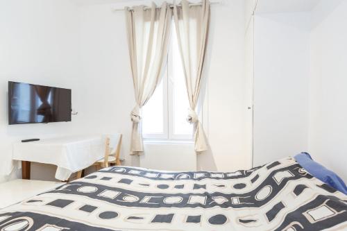 une chambre avec un lit, un bureau et une télévision dans l'établissement Studio Maine - Montparnasse Paris 14th, à Paris