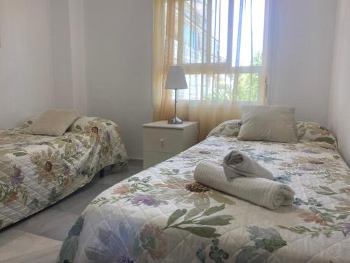 een slaapkamer met twee bedden, een lamp en een raam bij Carihuela Plaza del Remo in Torremolinos