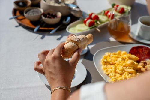 a person holding a piece of food on a table with breakfast foods at Scardona Park Luxury Accommodation in Skradin