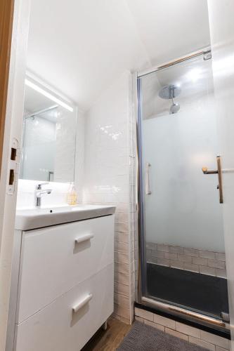 une salle de bain blanche avec une douche et un lavabo dans l'établissement Loft 1 BR Marais, Notre Dame AC by LCC Agency, à Paris