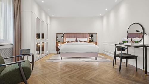 a white bedroom with a bed and a desk at Hotel Bristol Berlin in Berlin