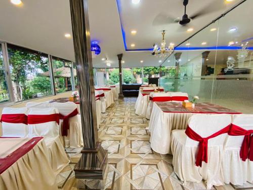 a restaurant with white tables and red chairs at Motherland Resort in Sauraha