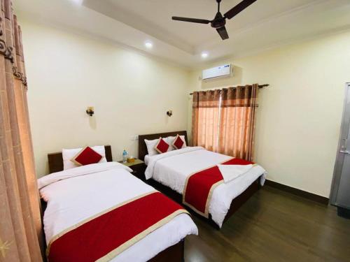 a bedroom with two beds and a ceiling fan at Motherland Resort in Sauraha