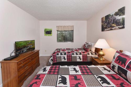 a bedroom with two beds and a flat screen tv at Bearly Ober By Colonial Properties in Gatlinburg