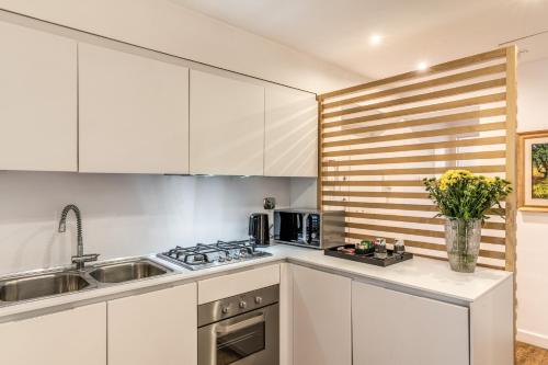 a kitchen with white cabinets and a sink at Trevi Beau Boutique Hotel in Rome
