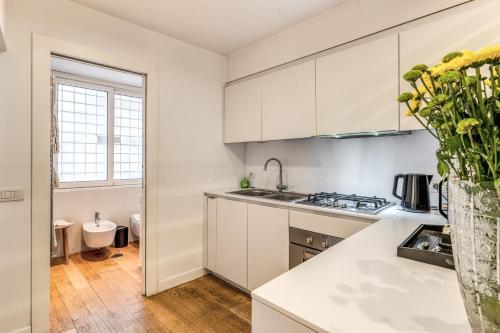 a kitchen with white cabinets and a vase of flowers at Trevi Beau Boutique Hotel in Rome