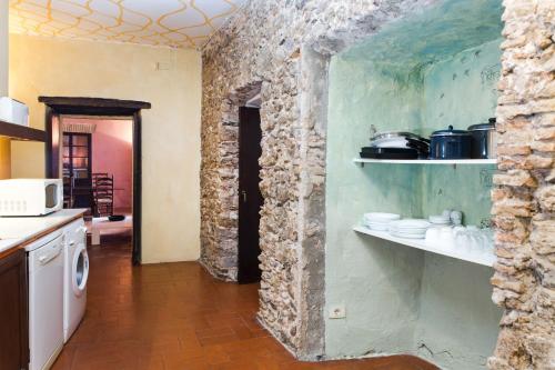 Una cocina con una pared de piedra con estantes. en Apartaments Can Gibert, en Castelló d'Empúries
