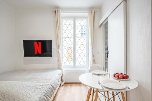 - une chambre avec un lit, une table blanche et une fenêtre dans l'établissement Studio Roger - Montparnasse Paris 14th, à Paris