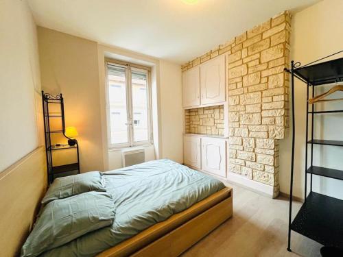 une chambre avec un lit et un mur de briques dans l'établissement Appartement T3 4 à 6 personnes, à Villeurbanne