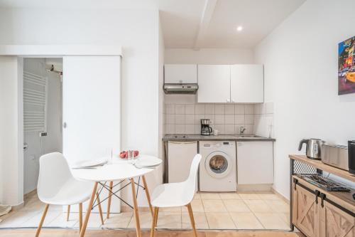 une cuisine avec une table et des chaises ainsi qu'un lave-linge dans l'établissement Studio Roger - Montparnasse Paris 14th, à Paris