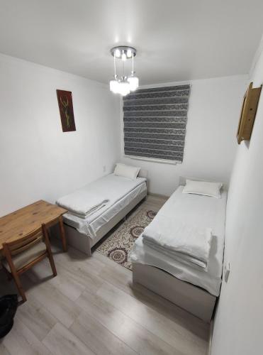 a room with two beds and a wooden table at Marsad in Kazarman