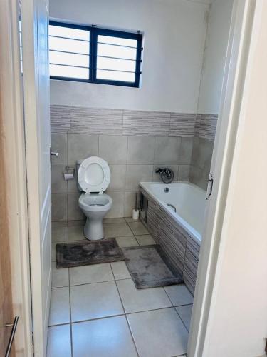 a bathroom with a toilet and a bath tub at 02 in Bel Aire place in Kempton Park