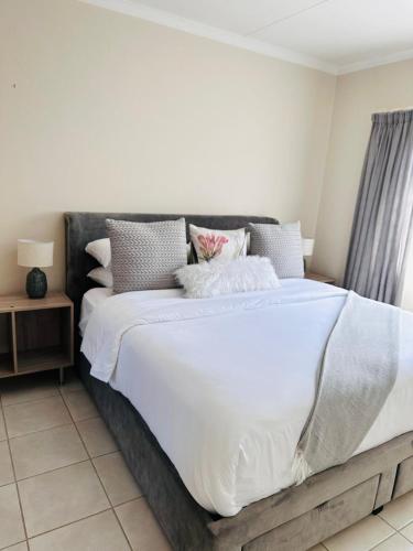 a bedroom with a large bed with white sheets and pillows at 02 in Bel Aire place in Kempton Park
