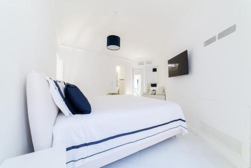 a white bedroom with a white bed with blue pillows at Ravello suite in Ravello